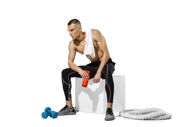 Resting. Stylish young male athlete practicing on white studio wall