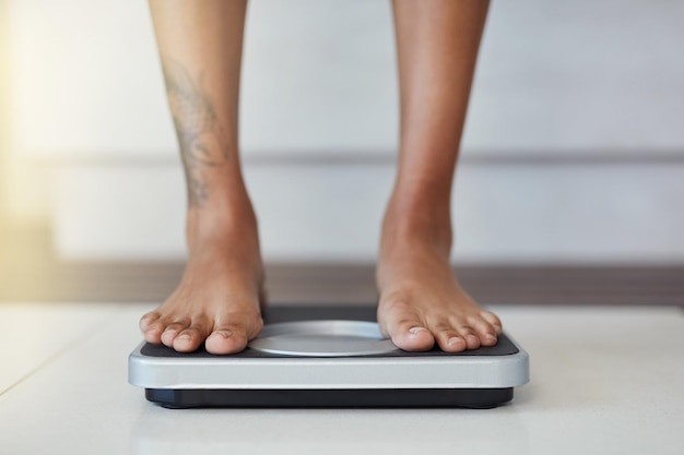 And the results are in Closeup shot of a woman weighing herself on a scale at home