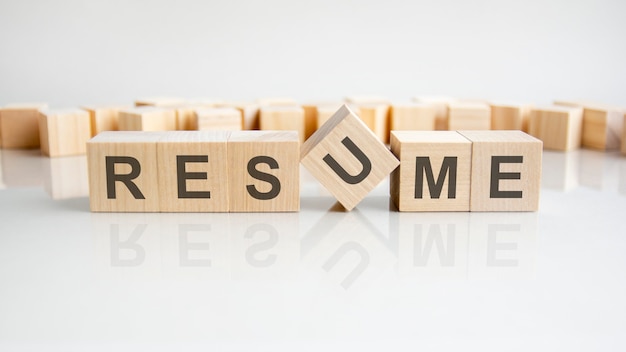 Resume - word of wooden blocks with letters on a gray background. Reflection of the caption on the mirrored surface of the table. Selective focus.