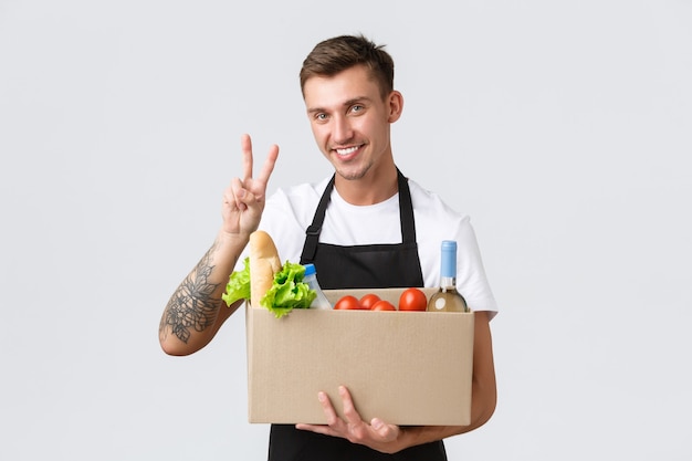 Retail grocery shopping and delivery concept charismatic handsome salesman courier in black apron sh...