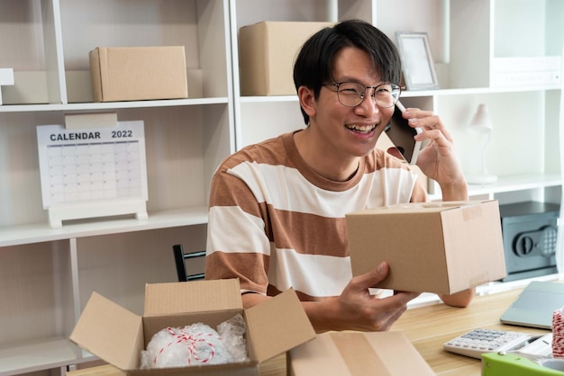 Retailer holding a parcel post while talking with his customer on the mobile phone