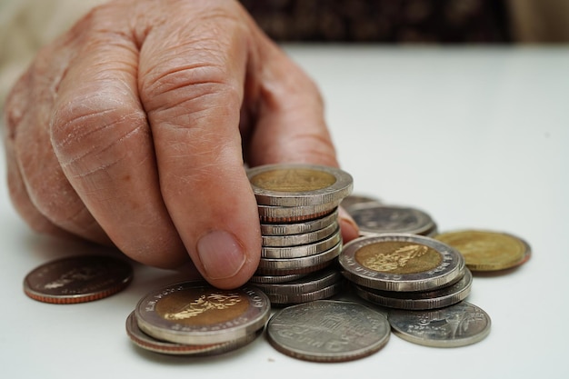 Retired elderly woman counting coins money and worry about monthly expenses and treatment fee payment