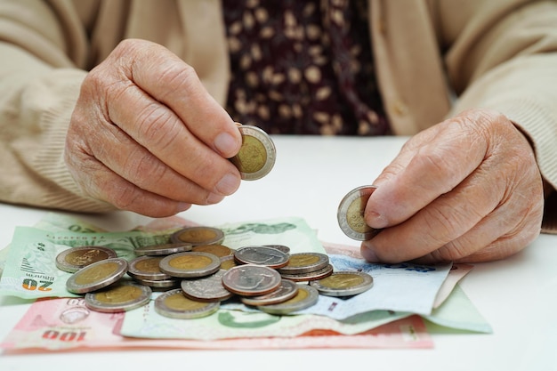 Retired elderly woman counting coins money and worry about monthly expenses and treatment fee payment