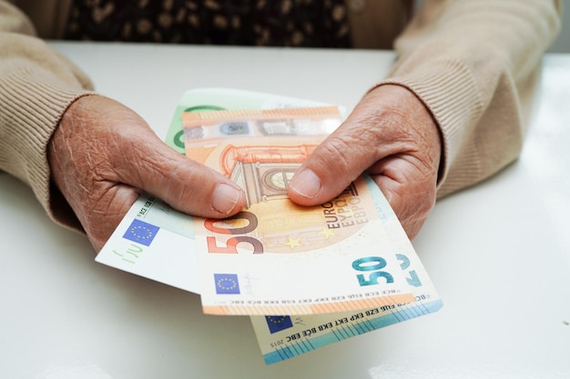 Retired elderly woman holding Euro banknotes money and worry about monthly expenses and treatment