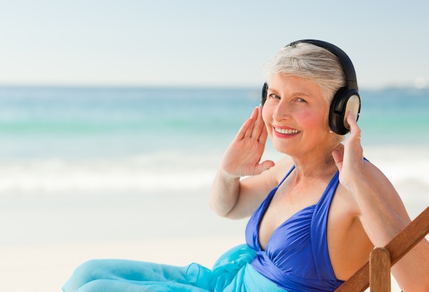 Retired woman listening to music at the beach