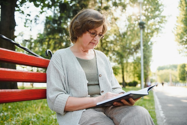 Retired woman reading a book on the bench