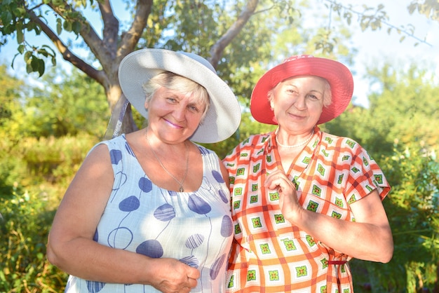 Retired women best friends in hats walk happily in the garden