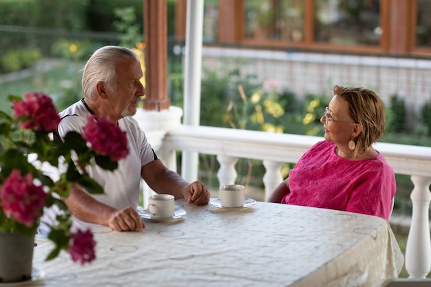 Retirement concept Two senior man and woman drinking coffee and smiling or discussing future plan after retire Mature couple drinking coffee on porch