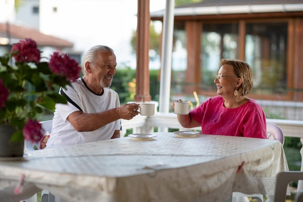 Retirement Senior couple drinking coffee on porch in their house Two mature man and woman drinking coffee and smiling or discussing plans for future