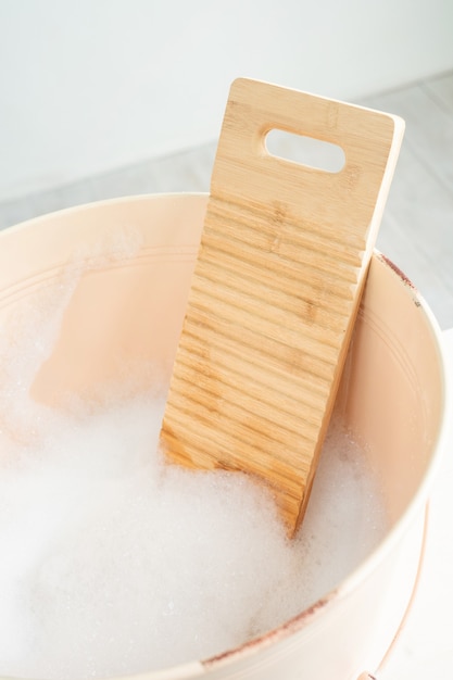 Retro basin with foam and a board for washing on a white wooden table. Eco-friendly hand wash. Zero waste.