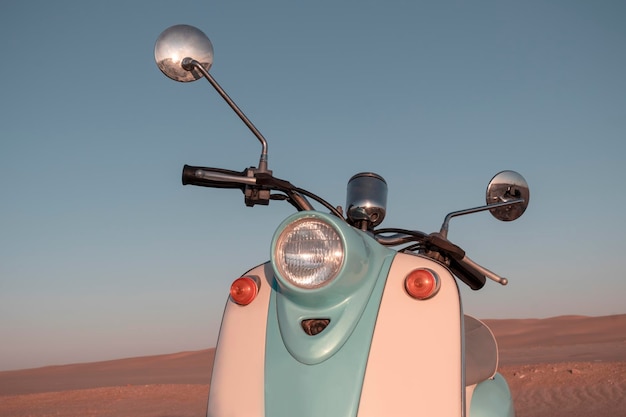 Retro blue scooter at sunset in the golden sand of the Namib Desert