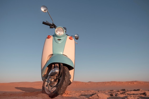 Retro blue scooter at sunset in the golden sand of the Namib Desert