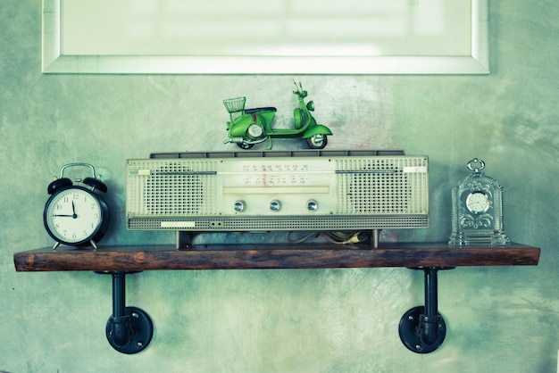 Retro broadcast radio receiver on wooden shelf with concrete wall background.