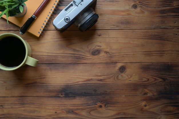 A retro camera notebook and coffee cup on wooden table