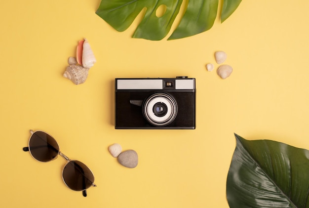 Retro camera in a summer composition on a bright yellow background Flat lay top view