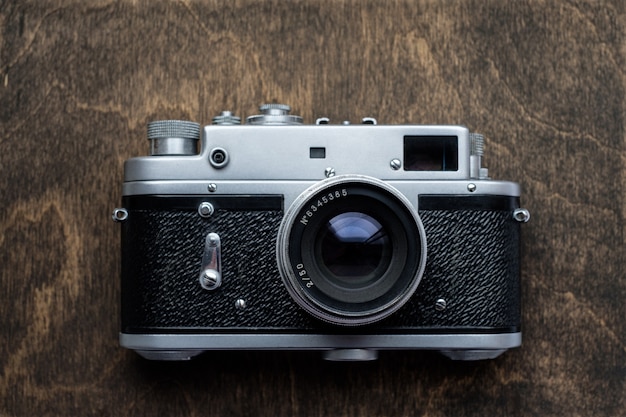 Retro camera on wood table background, vintage rangefinder film camera, flat top view