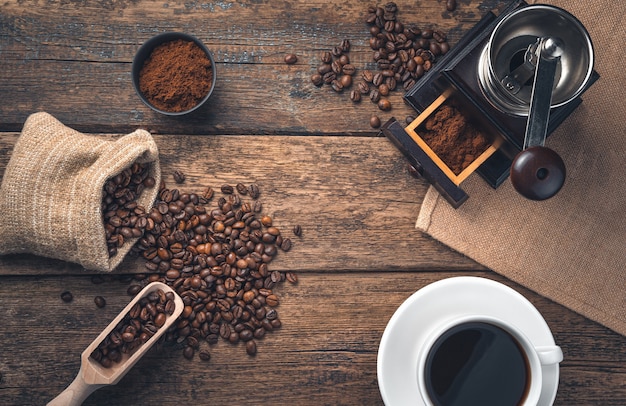 Retro coffee wall with copy space. A cup of coffee, coffee beans and a coffee grinder on a wooden wall. Top view.