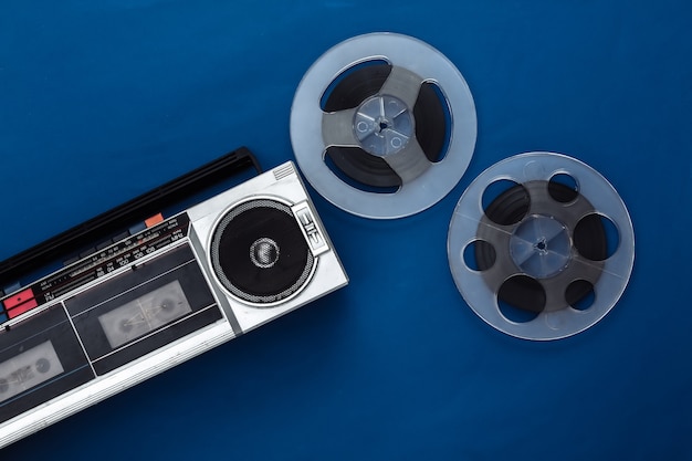 Retro flat lay. Retro portable stereo cassette recorder and audio magnetic tape reel on classic blue