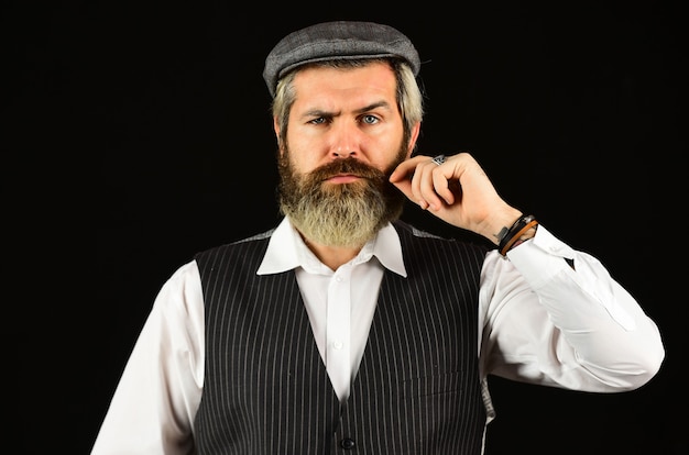 Retro gentlemen. Mature handsome man. Man in vintage style hat. Brutal bearded hipster vest. Old fashioned. Real masculinity. Masculine appearance. Bearded guy on black background. Beard grooming.