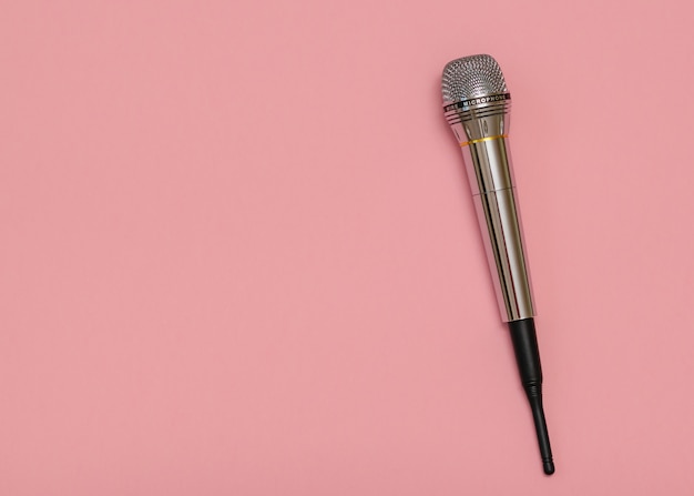 Retro microphone with wire on pink surface