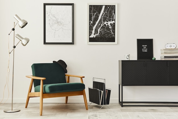 Retro and minimalist compositon of living room interior with design armchair, two map, lamp, decoration, white wall and personal accessories.. Modern home decor.