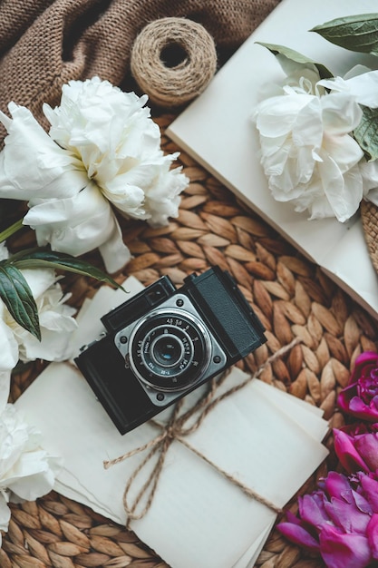 Photo retro photo camera with book and fresh pink peony flowers