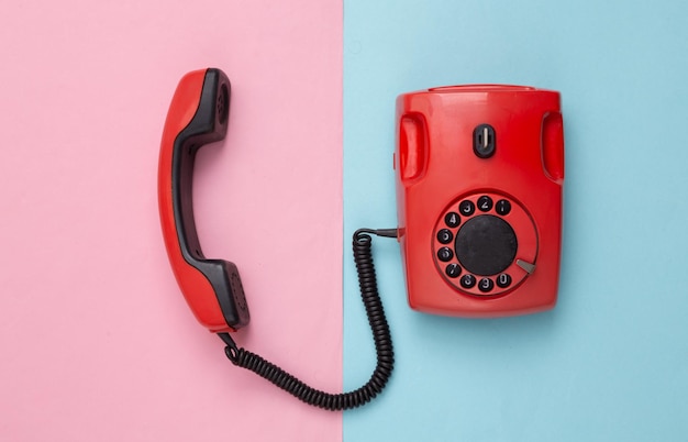 Retro red old fashioned rotary phone on pink blue background Top view