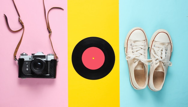 Retro still life. Old fashioned sneakers, vinyl record, vintage film camera. Top view. Pop art flat lay