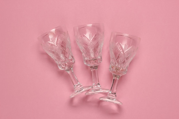 Retro style faceted crystal wine glasses on pink pastel background.