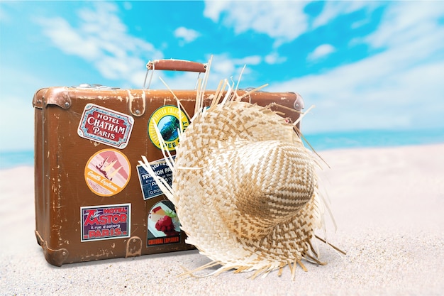 Retro suitcase with travel hat on tropical background