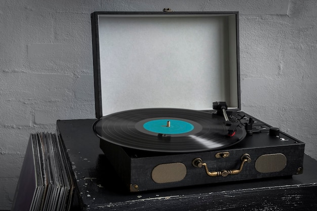 Retro turntable with playing vinyl disc and stack of records