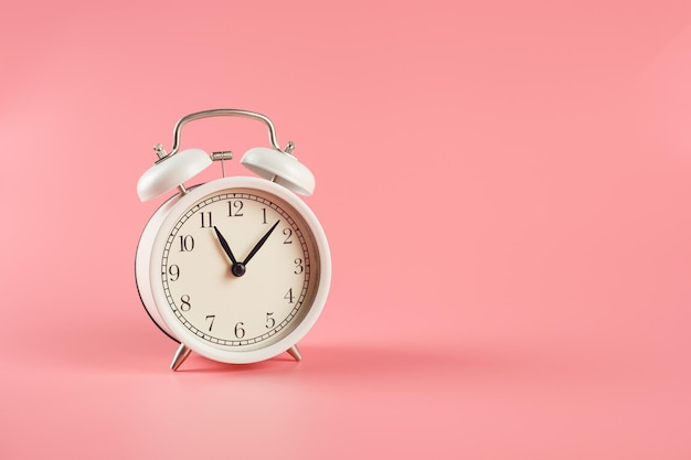 Retro white alarm clock on pink background.