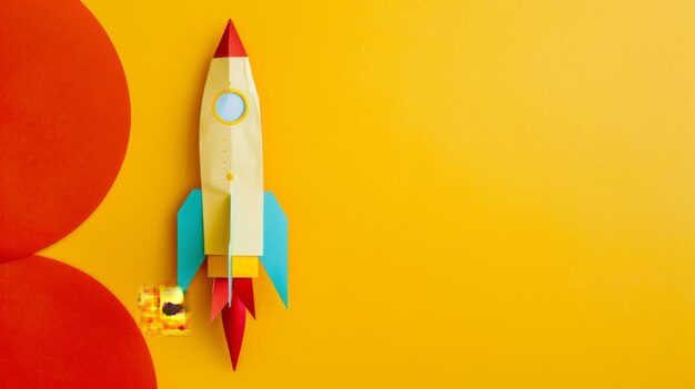 Photo a retrostyle toy rocket with blue wings and a red nose stands against a bright yellow background suggesting a journey ready to begin