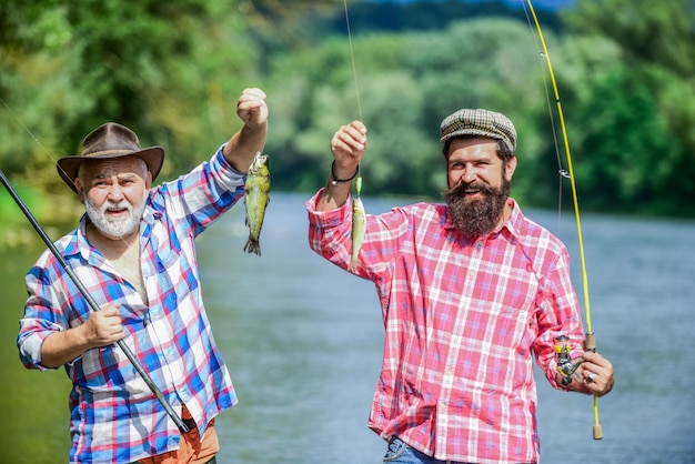 Reunited and it feel so good father and son fishing summer weekend mature men fisher hobby and sport activity Trout bait two happy fisherman with fishing rods male friendship family bonding