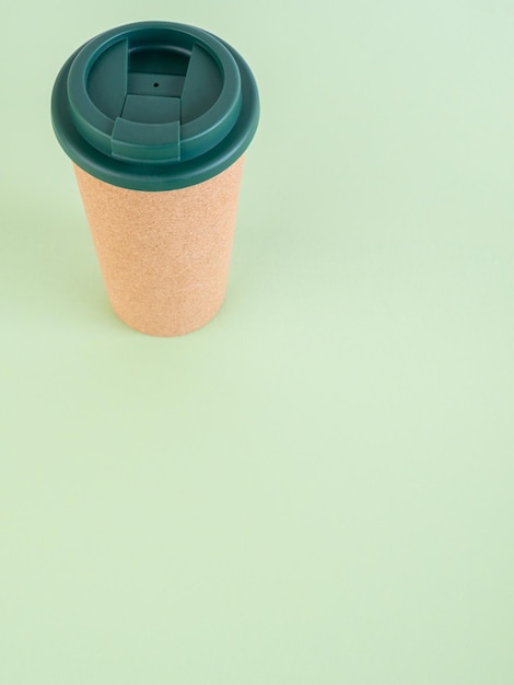 Photo reusable cup at the top of the image on green background with copy space