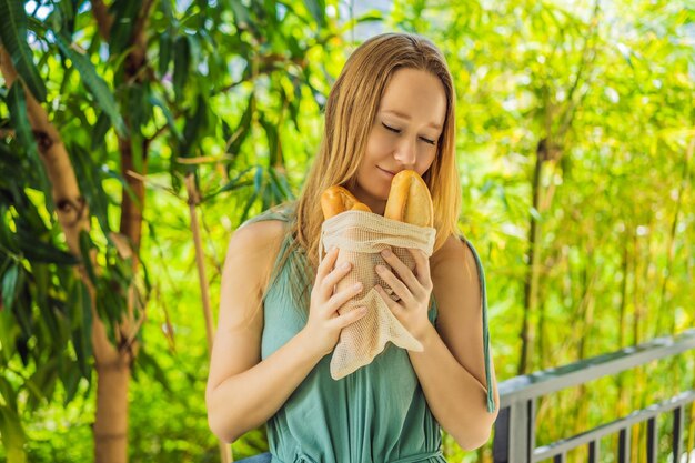 Reusable grocery bags with bread in the hands of a young woman Zero waste shopping Zero waste concept