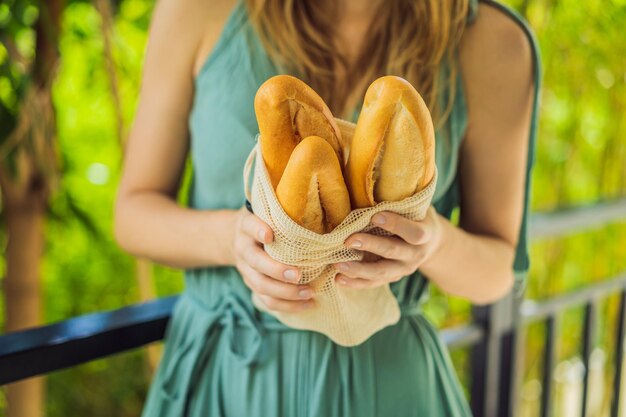 Reusable grocery bags with bread in the hands of a young woman Zero waste shopping Zero waste concept