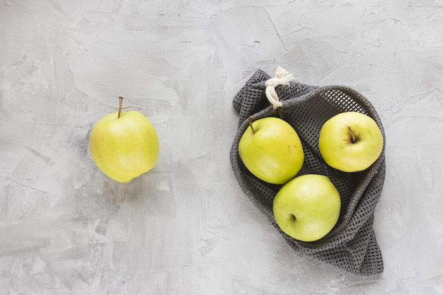 Reusable shopping mesh bag on gray with apples background Zero waste no plastic