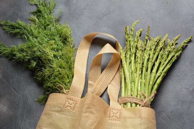 Reusable zero waste textile product bag filled with green asparagus and parsley