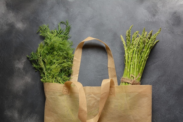 Reusable zero waste textile product bag filled with green asparagus and parsley