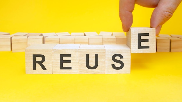 Reuse symbol businessman turns wooden cubes the words renew beautiful yellow background copy space business concept