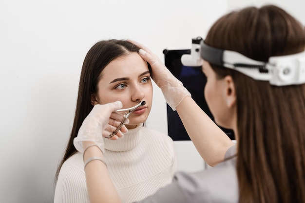 Rhinoscopy of woman nose Consultation with ENT doctor Otolaryngologist examines girl nose before procedure of endoscopy of nose