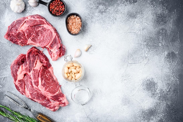 Rib eye steak of beef marbled meat or scotch fillet set on gray stone background top view flat lay with copy space for text