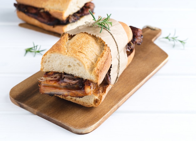 Rib sandwich in barbecue sauce on a white wooden base. Copy space.