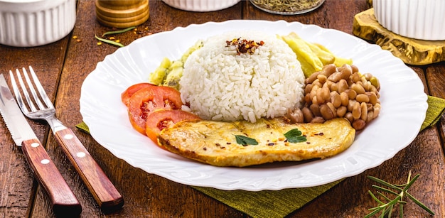 Rice and beans served with french fries grilled chicken fillet and salad typical brazilian meal