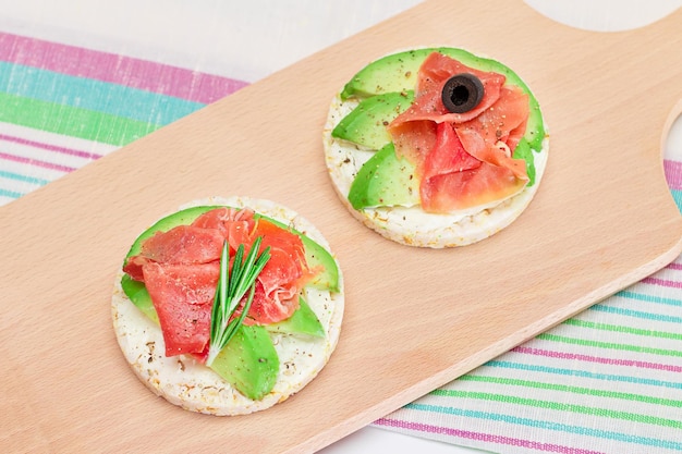 Rice cake sandwich with avocado jamon olives and rosemary