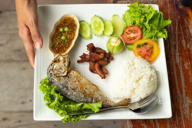 Photo rice, chili sauce, fish and pork fried with vegetables on a white plate