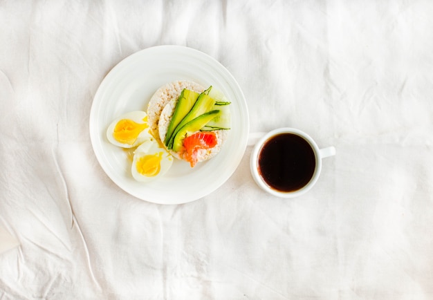 Rice crispy cakes with avocado and fresh salted salmon.Top view. Space for text. High protein and low carbohydrate meal. White linen tablecloth background.