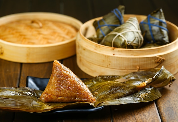 Rice dumplings zongzi and bamboo steamer on wooden table