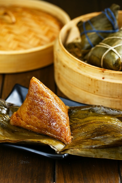 Rice dumplings zongzi and bamboo steamer on wooden table